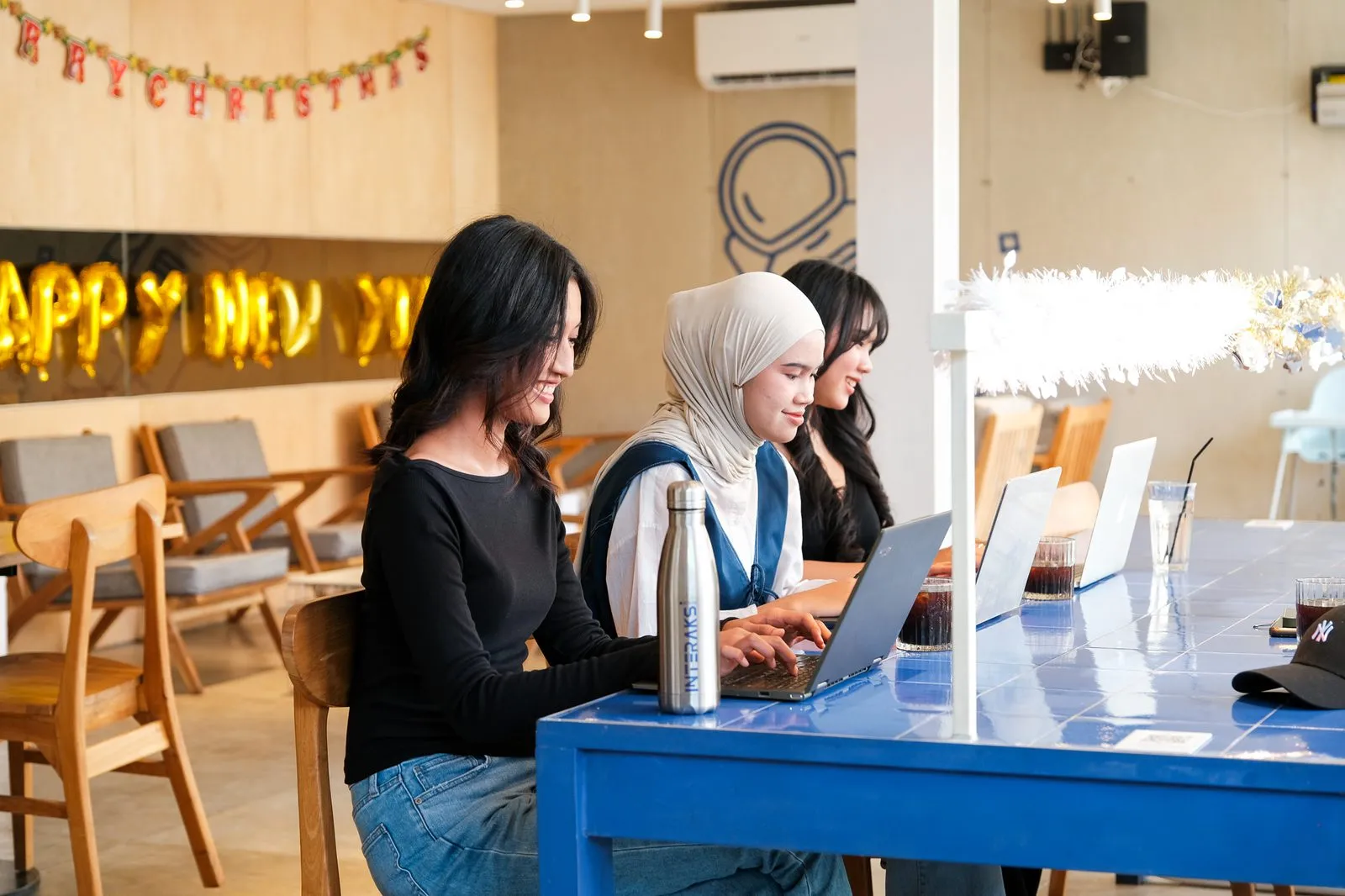 Pengunjung bekerja dan berbincang di meja keramik biru khas Interaksi Space